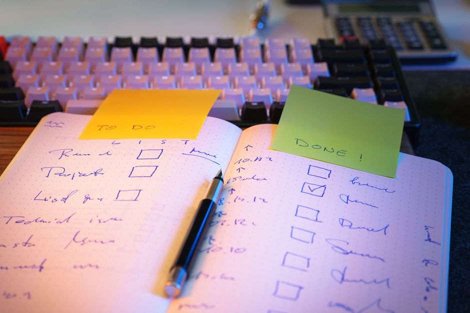 Carnet ouvert avec une liste de tâches à cocher posée devant un clavier et une calculatrice